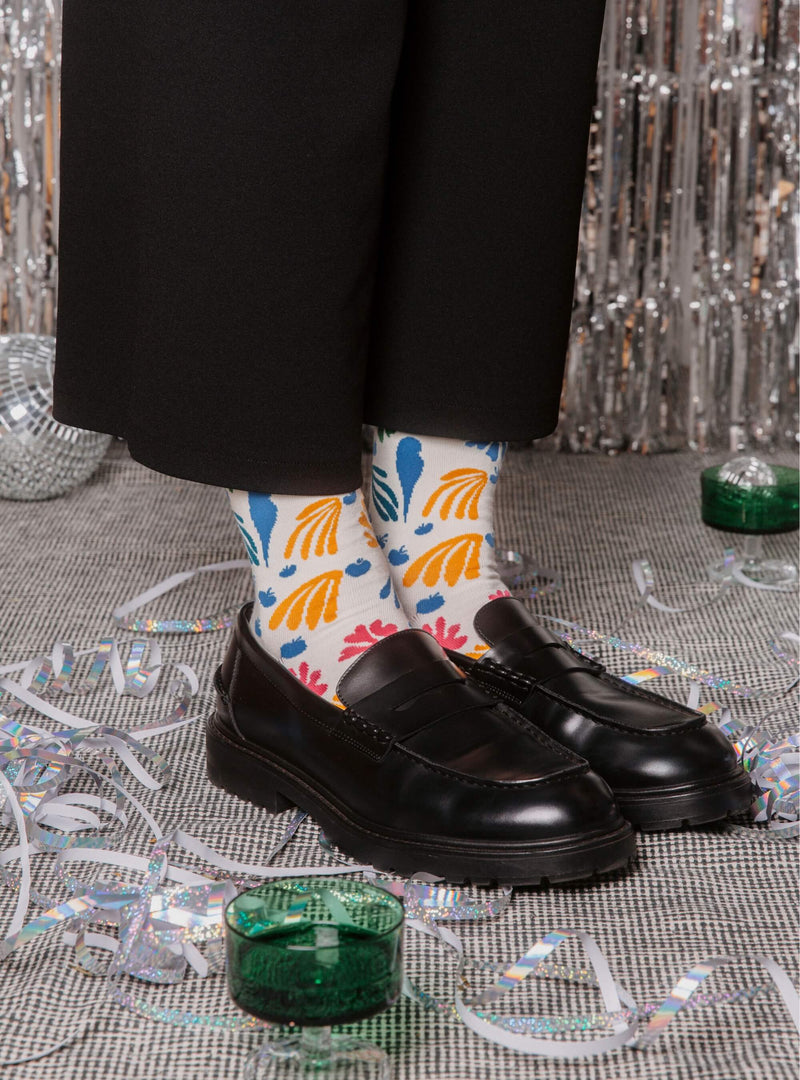 De Parkiet en de Zeemeermin sokken van Kunstsokken naar Henri Matisse, gedragen met zwarte loafers tussen feestslingers